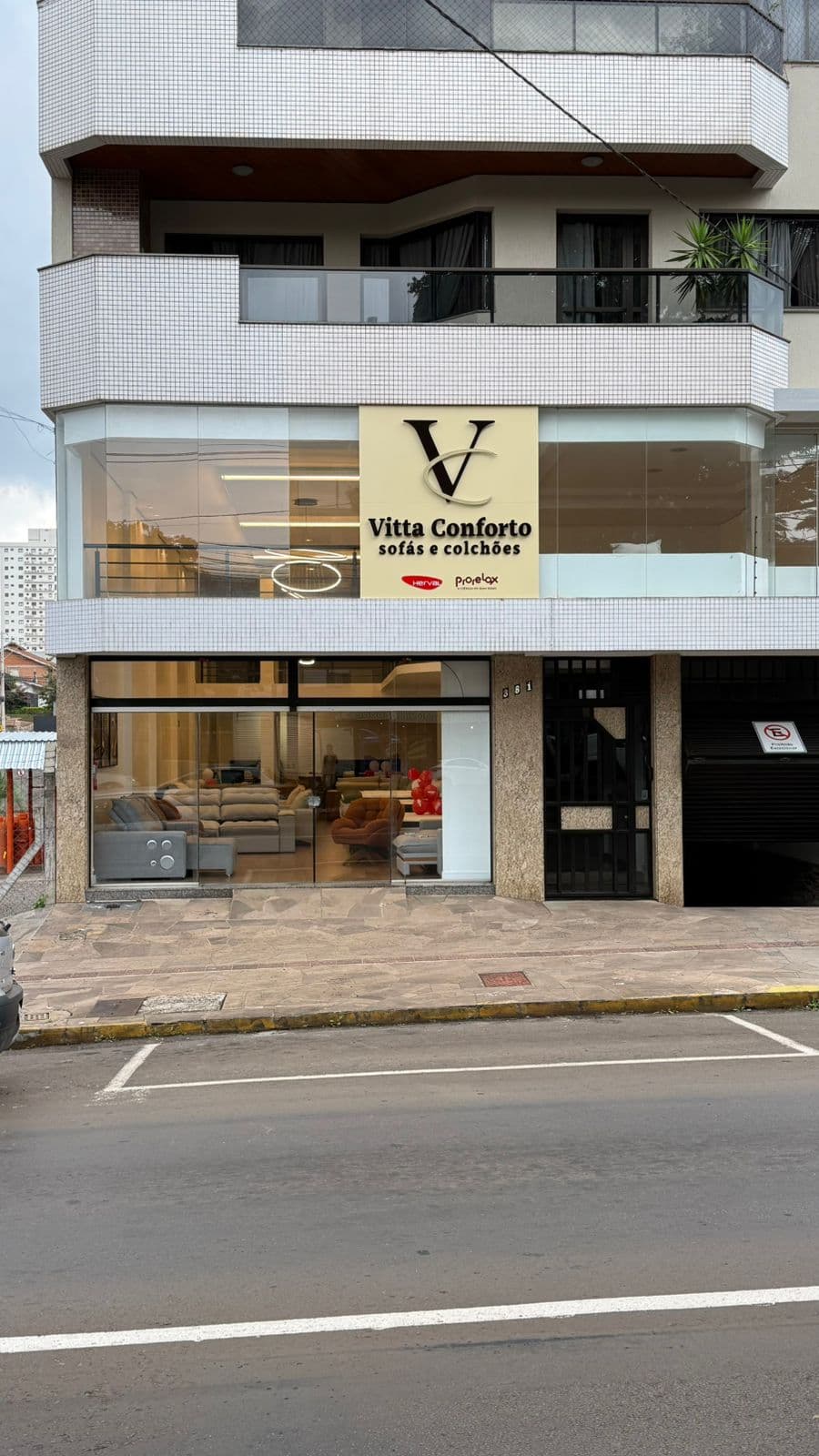 Fachada da loja Vitta Conforto com vitrines de vidro exibindo sofás e letreiro dourado.